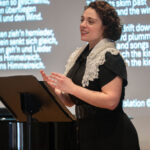 Shari Feldman singing in front of slides with lyrics